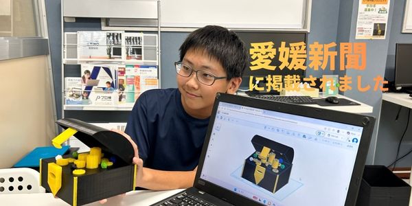 愛媛新聞に掲載されたプログラミング教室TiNOの生徒が、3Dプリンターで制作した宝箱型貯金箱と3Dモデルを紹介している写真
